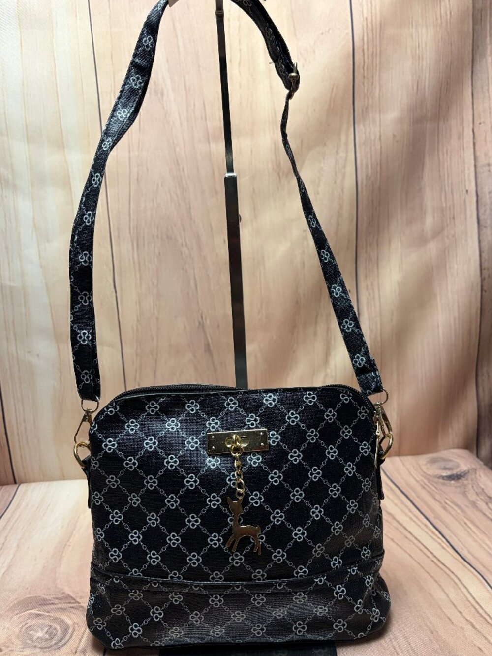 Black geometric-patterned shoulder bag featuring a distinctive gold-toned charm